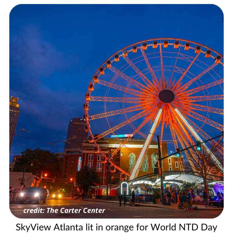 Photo of a Ferris wheel in Atlanta. It is illuminated in orange light.