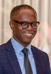 photo of a man wearing glasses and a blue suit